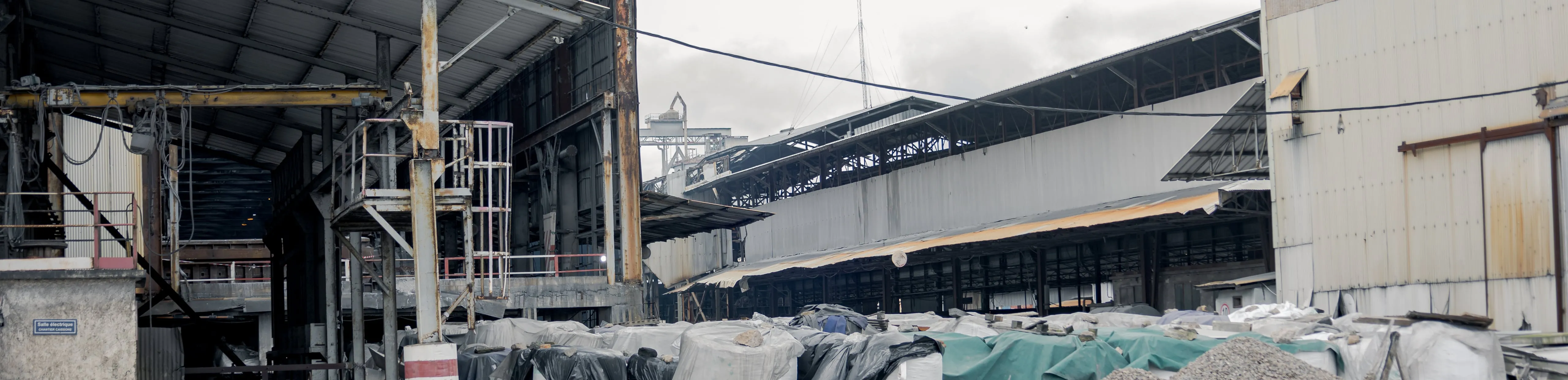 Industrial halls and a storage area of covered bags, under an overcast sky