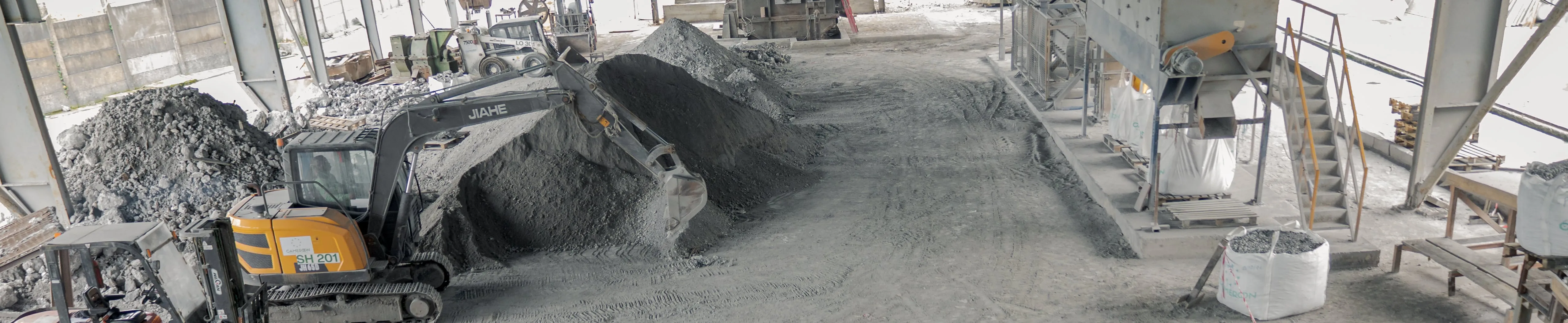 Covered workshop, with an excavator moving material and a bagging station on the right